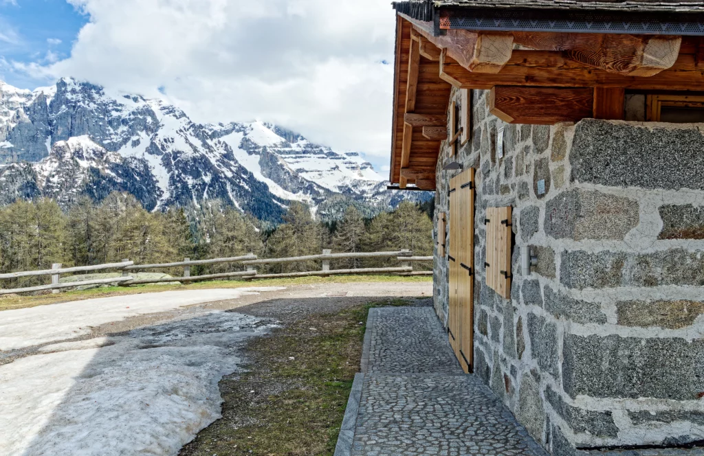 Il lato di una delle malghe con il panorama montano con la neve al lato sinistro della foto.